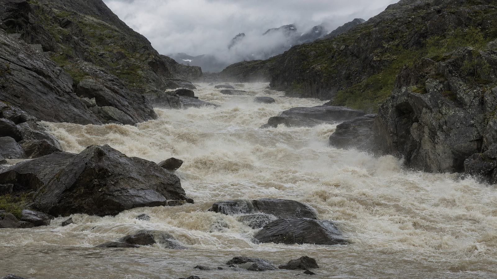 Torrent gonflé et chargé de blocs emportant un tronçon de sentier dans une vallée pyrénéenne après de fortes pluies