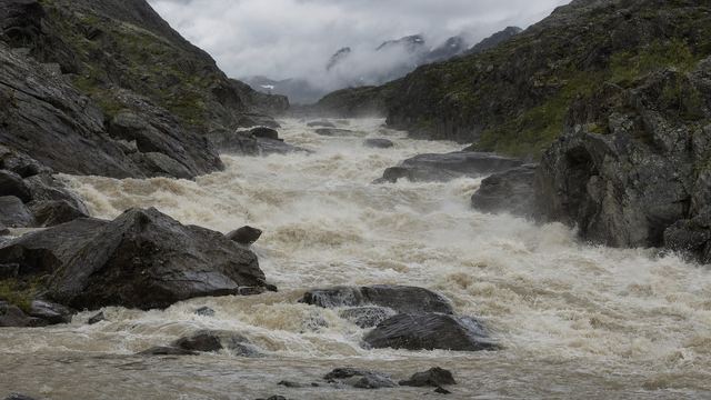 Torrent gonflé et chargé de blocs emportant un tronçon de sentier dans une vallée pyrénéenne après de fortes pluies
