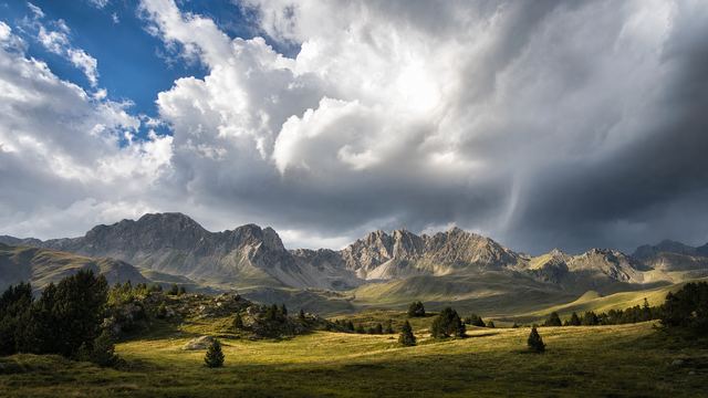 Cumulonimbus sombre qui se forme au-dessus d’une crête pyrénéenne en fin de matinée, avec un randonneur au loin